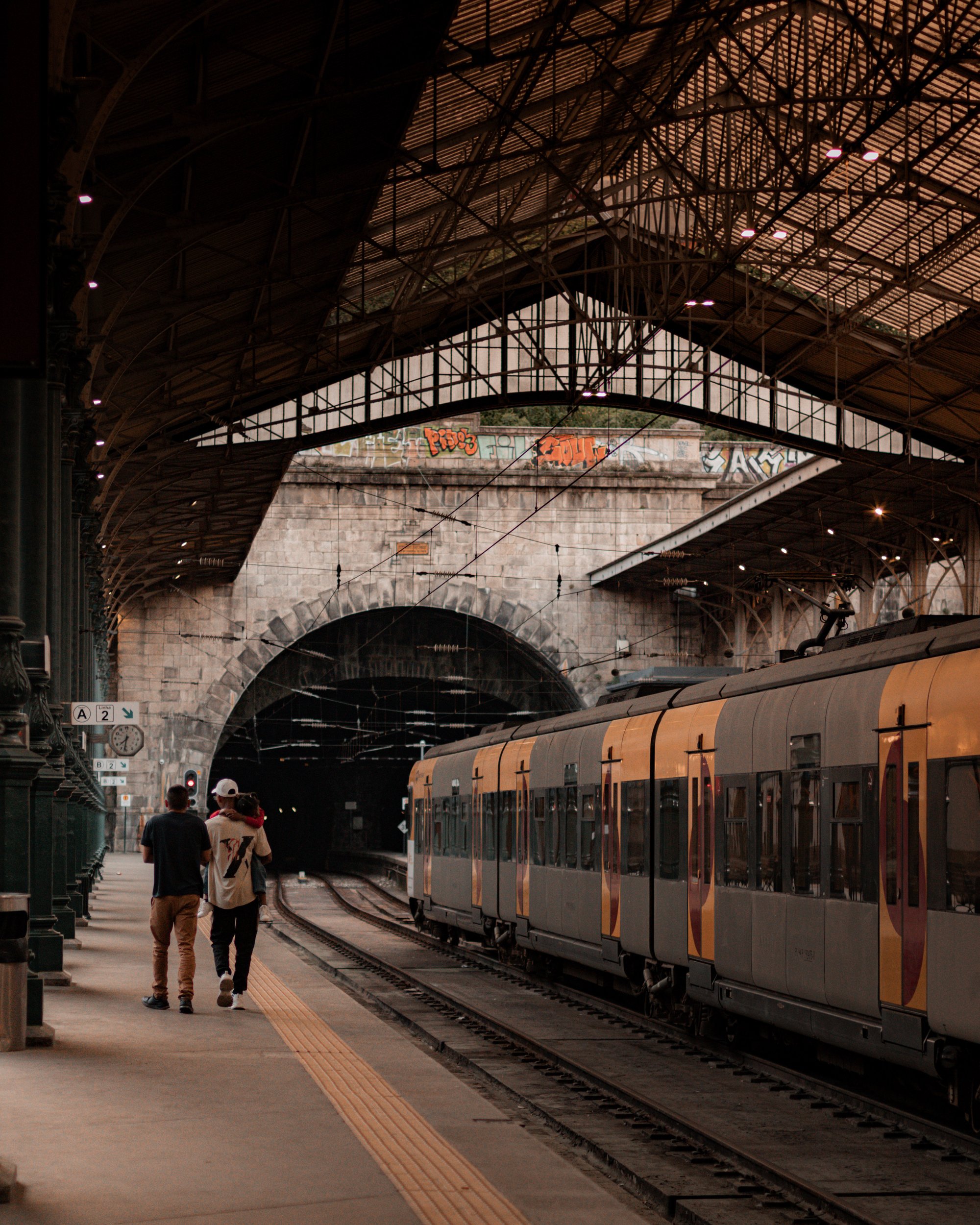Train at São Bento station in Porto beneath an iron roof with passengers on the platform